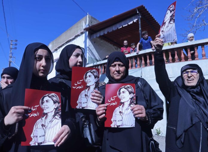 Mourners hold portraits of the Lebanese journalist Amal Khalil, after leaders accused Israel of a war crime over the airstrike that killed her. Photograph: Mahmoud Zayyat/AFP/Getty Images