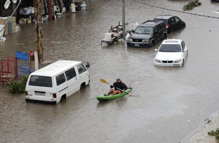 TOPSHOT - A Lebanese man uses a canoe as means of transportation on a flooded road due to heavy rain, at the southern entrance of the capital Beirut on December 9, 2019. (Photo by Anwar AMRO / AFP) (Photo by ANWAR AMRO/AFP via Getty Images)